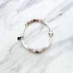 Beaded bracelet with a silver cross charm on a marble surface, featuring John 3:16 Christian bracelet love