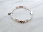 Beaded bracelet with a silver cross charm on a marble surface, featuring John 3:16 Christian bracelet love