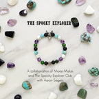 Bracelet with beads on a white surface surrounded by various stones, featuring 'The Spooky Explorer' branding with Aaron Sagers