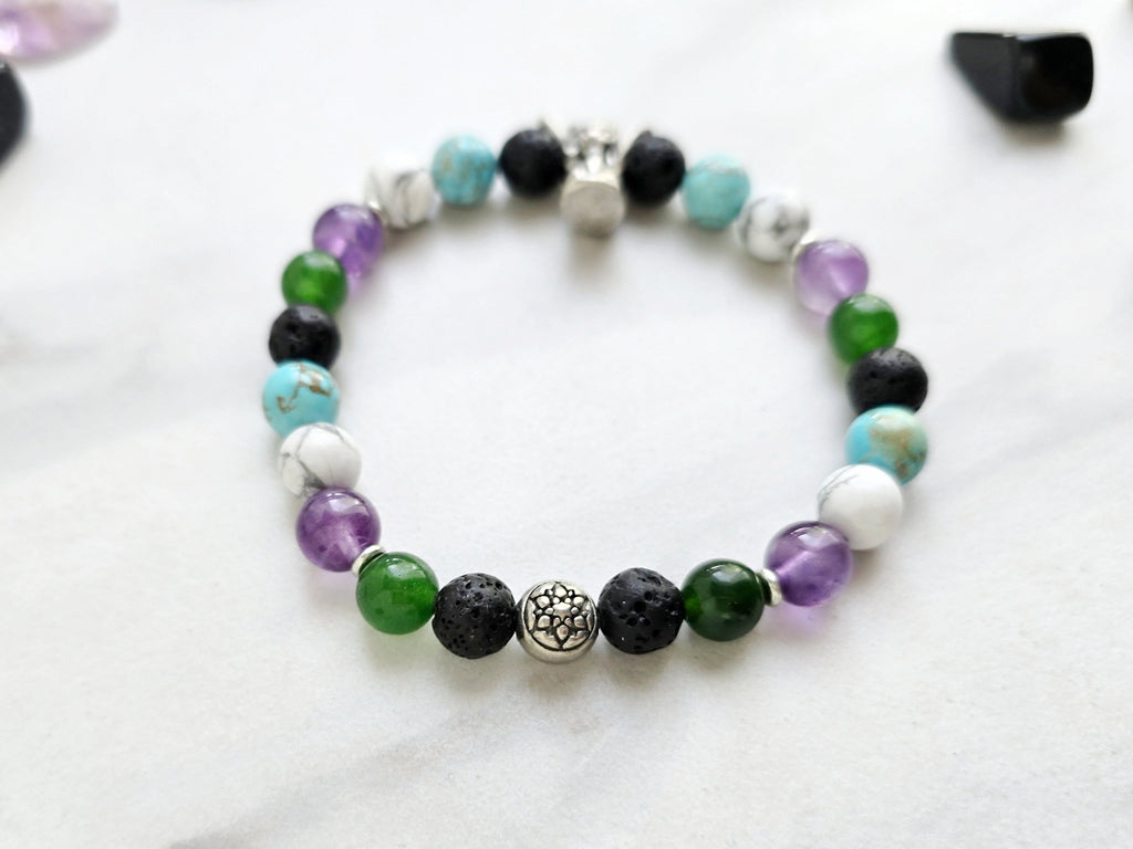 Bracelet with beads on a white surface surrounded by various stones, featuring 'The Spooky Explorer' branding with Aaron Sagers