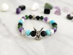 Bracelet with beads on a white surface surrounded by various stones, featuring 'The Spooky Explorer' branding with Aaron Sagers