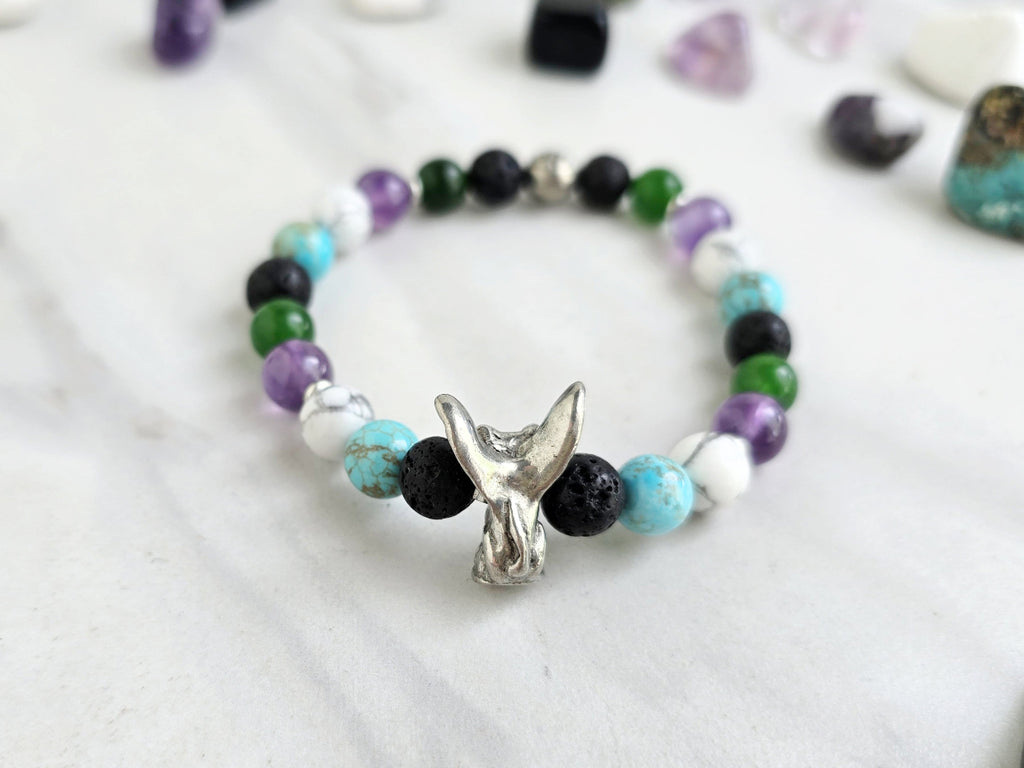 Bracelet with beads on a white surface surrounded by various stones, featuring 'The Spooky Explorer' branding with Aaron Sagers