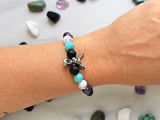 Bracelet with beads on a white surface surrounded by various stones, featuring 'The Spooky Explorer' branding with Aaron Sagers