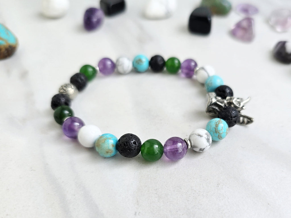 Bracelet with beads on a white surface surrounded by various stones, featuring 'The Spooky Explorer' branding with Aaron Sagers