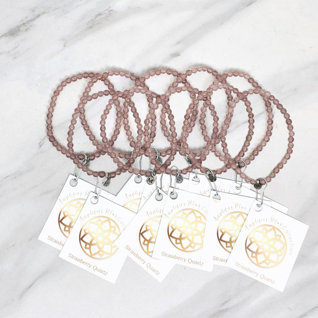 Two strawberry quartz beaded bracelets with matching tags on a marble surface. valentines day galentines gifts
