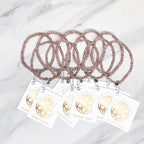 Two strawberry quartz beaded bracelets with matching tags on a marble surface. valentines day galentines gifts