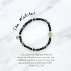 Black beaded bracelet with a cross charm on a white fabric background, the watcher Christian bracelet psalm 121:7-8